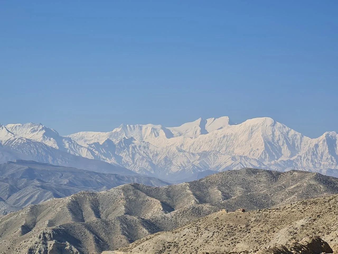 Arid Mustang foothills give way to a vast, snow-covered Himalayan wall.