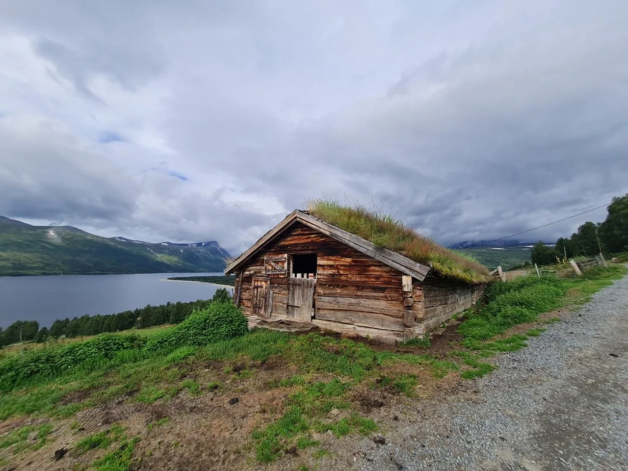 Historic hut with sod roof overlooking lake and mountains