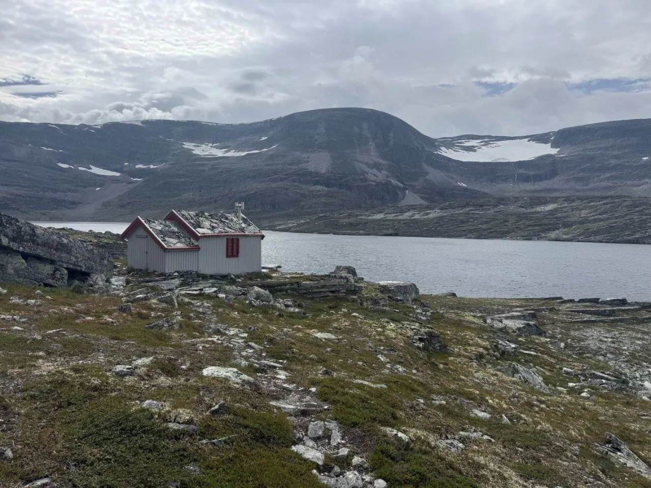 Hut by the lake with mountainous backdrop