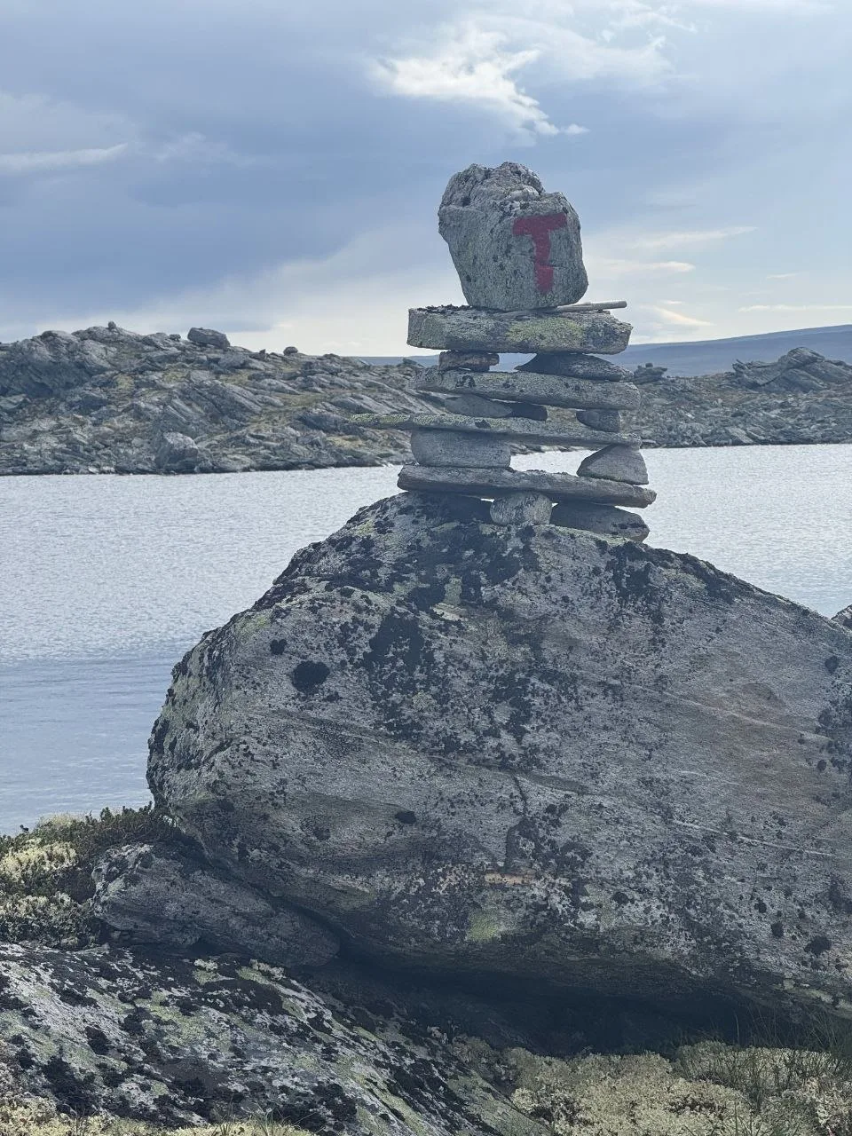 Stacked stones with red T trail marker by lakeside