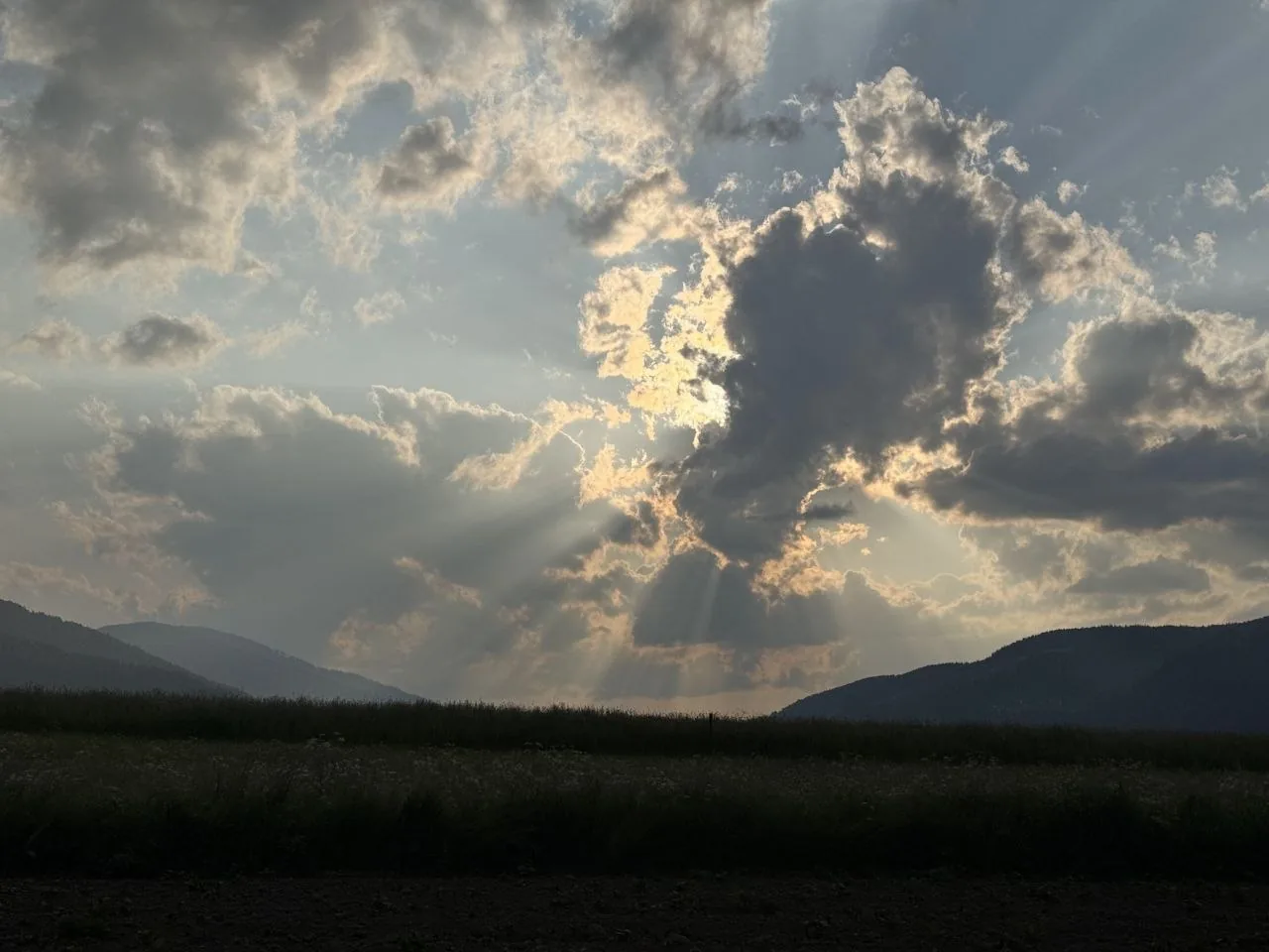 Crepuscular rays break through evening clouds over the Pusteria Valley floor.