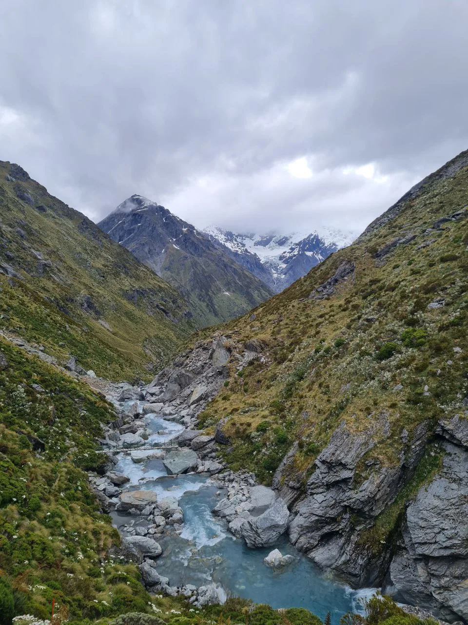 Glacial-blue Dart River flows beneath a swing bridge deep in the valley.