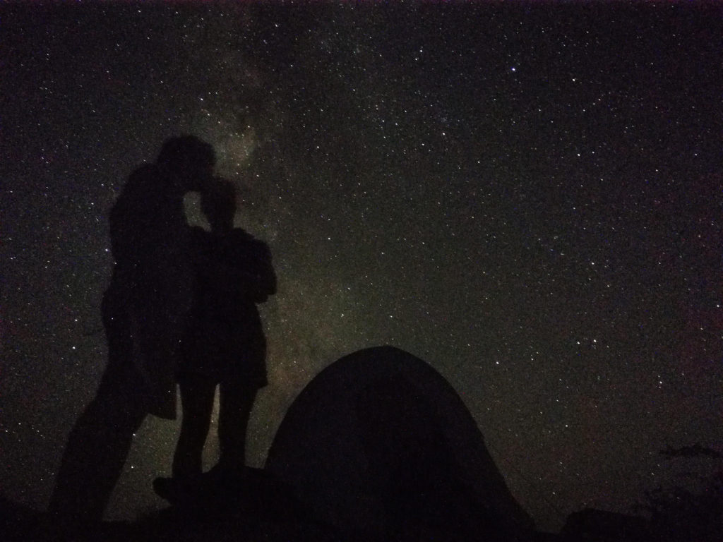 Canyonlands Murphy Trail: Night sky and milky way behind silhouette of couple and tent